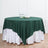 Green round tablecloth draped over a white table skirt with glassware on the table.