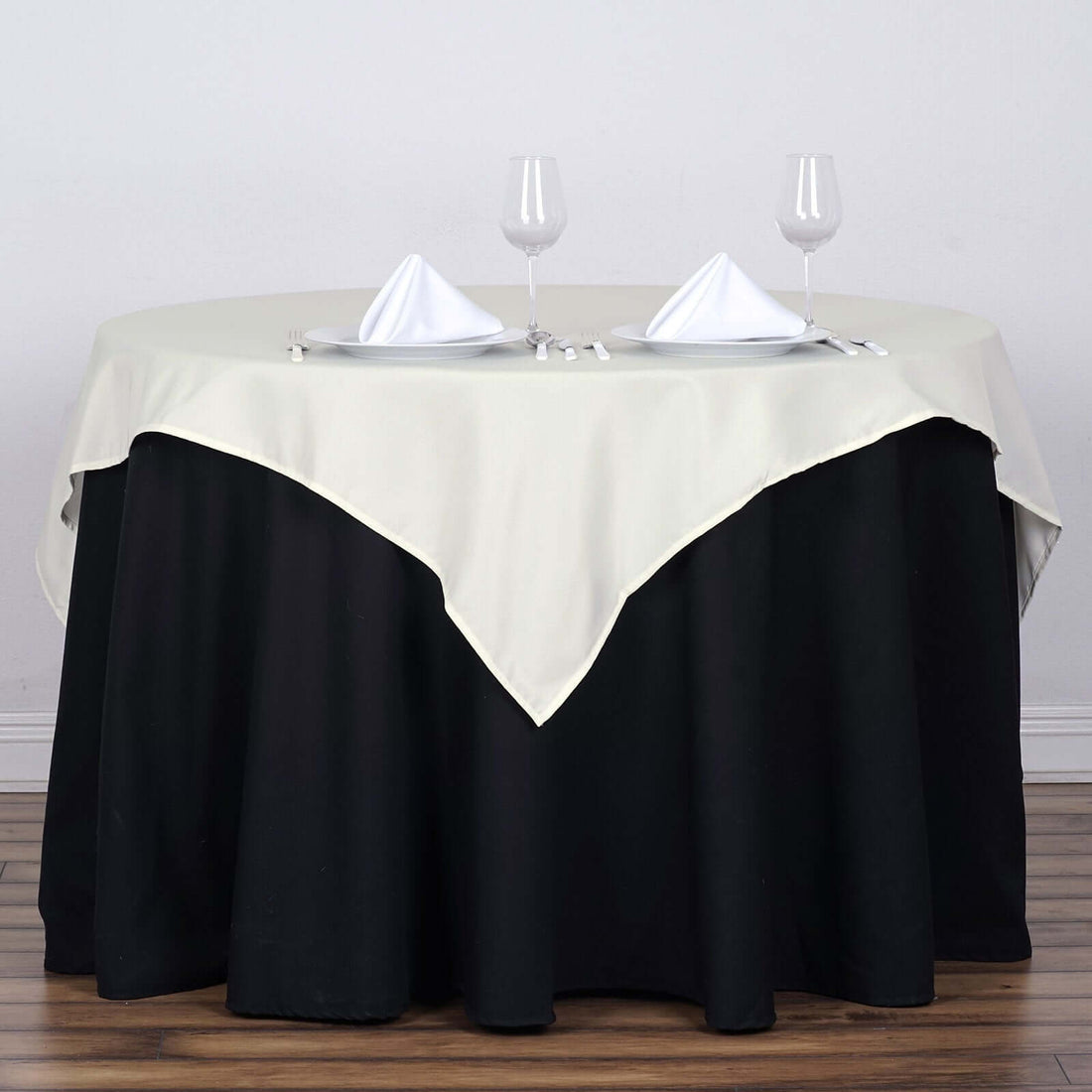Elegant round table with cream tablecloth set for dining.