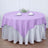 Round lavender tablecloth on a silver table skirt in a staged dining setting.