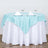 Round table set with aqua blue and white tablecloth, glasses, and napkins.