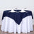 Navy tablecloth set on a round table with white skirt and elegant dining setup.