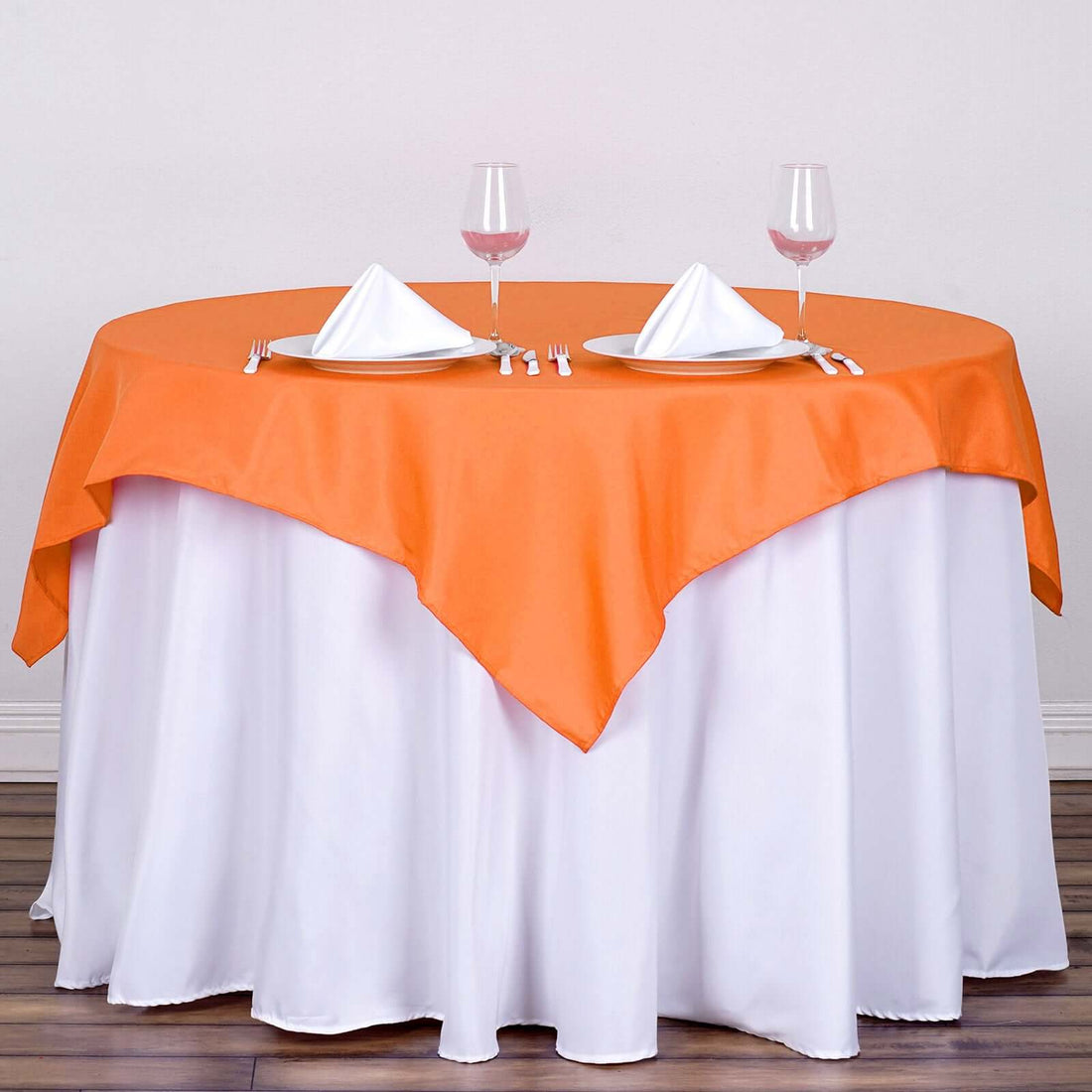 Round table set with orange tablecloth and white napkins in a dining setup.