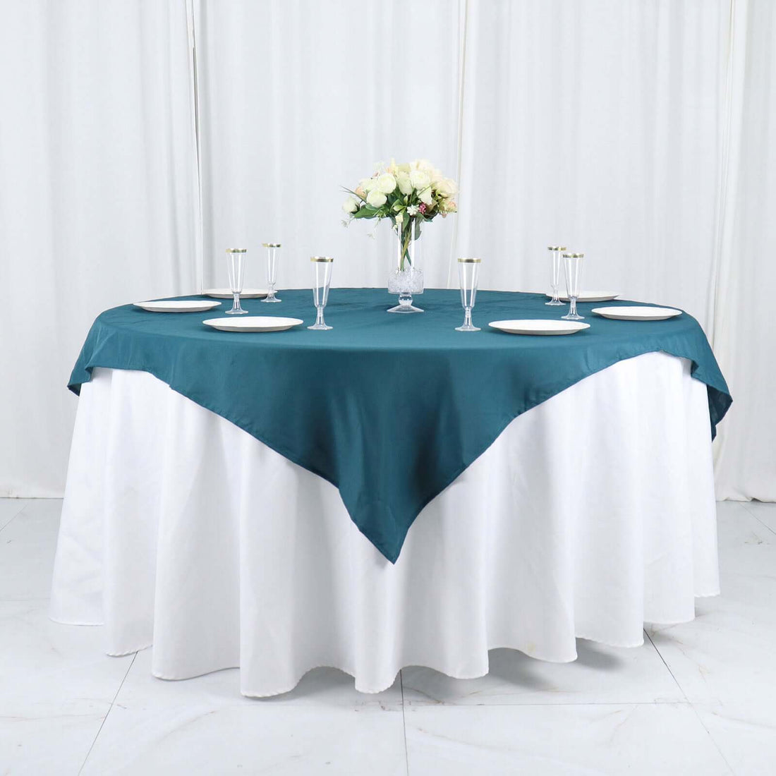Teal tablecloth draped over a round table set for an elegant dining experience.