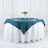 Teal tablecloth draped over a round table set for an elegant dining experience.