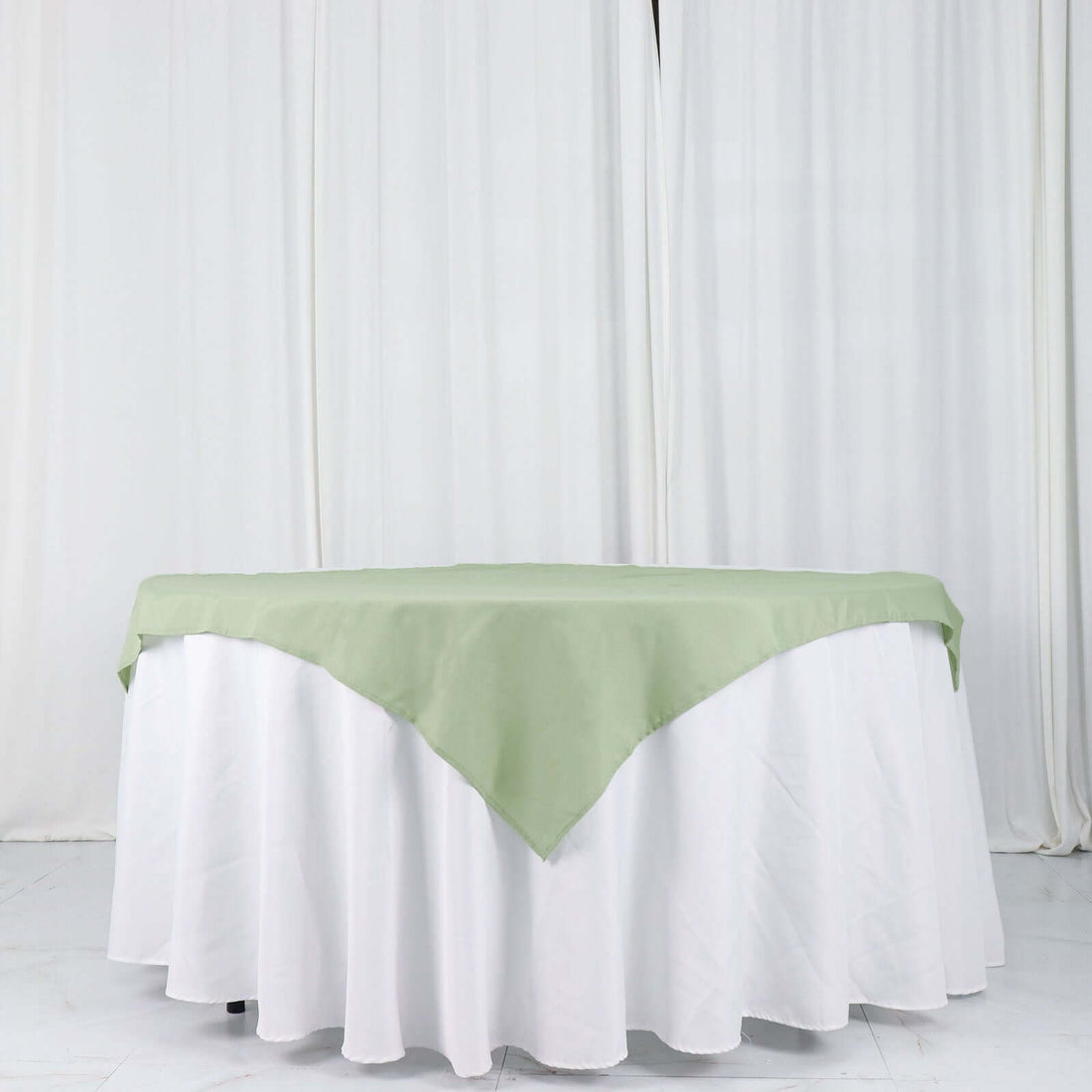 Green tablecloth draped over a white table with a smooth finish