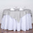 Round table set with a gray and white tablecloth, two napkins, and two wine glasses.