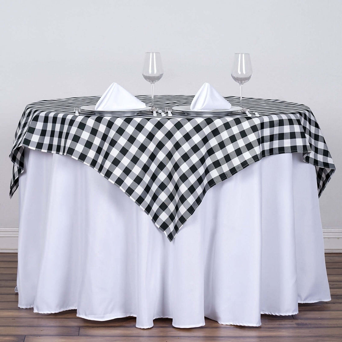 Black and white checkered tablecloth draped over a round table with glasses.