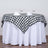 Black and white checkered tablecloth draped over a round table with glasses.