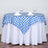 Round table set with blue and white checkered tablecloth and wine glasses.