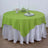 Green round tablecloth on a table with a white satin underlay.