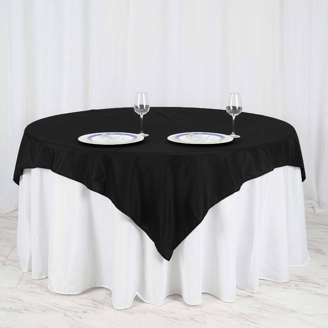 Elegant black tablecloth on a round table set for dining with plates and glasses.