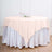 Round tablecloth in soft pink draped over a white satin table.