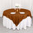 Brown round tablecloth draped over a white table with plates and glasses.