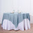 Round table with a blue tablecloth and white skirt. Elegant dining setup.
