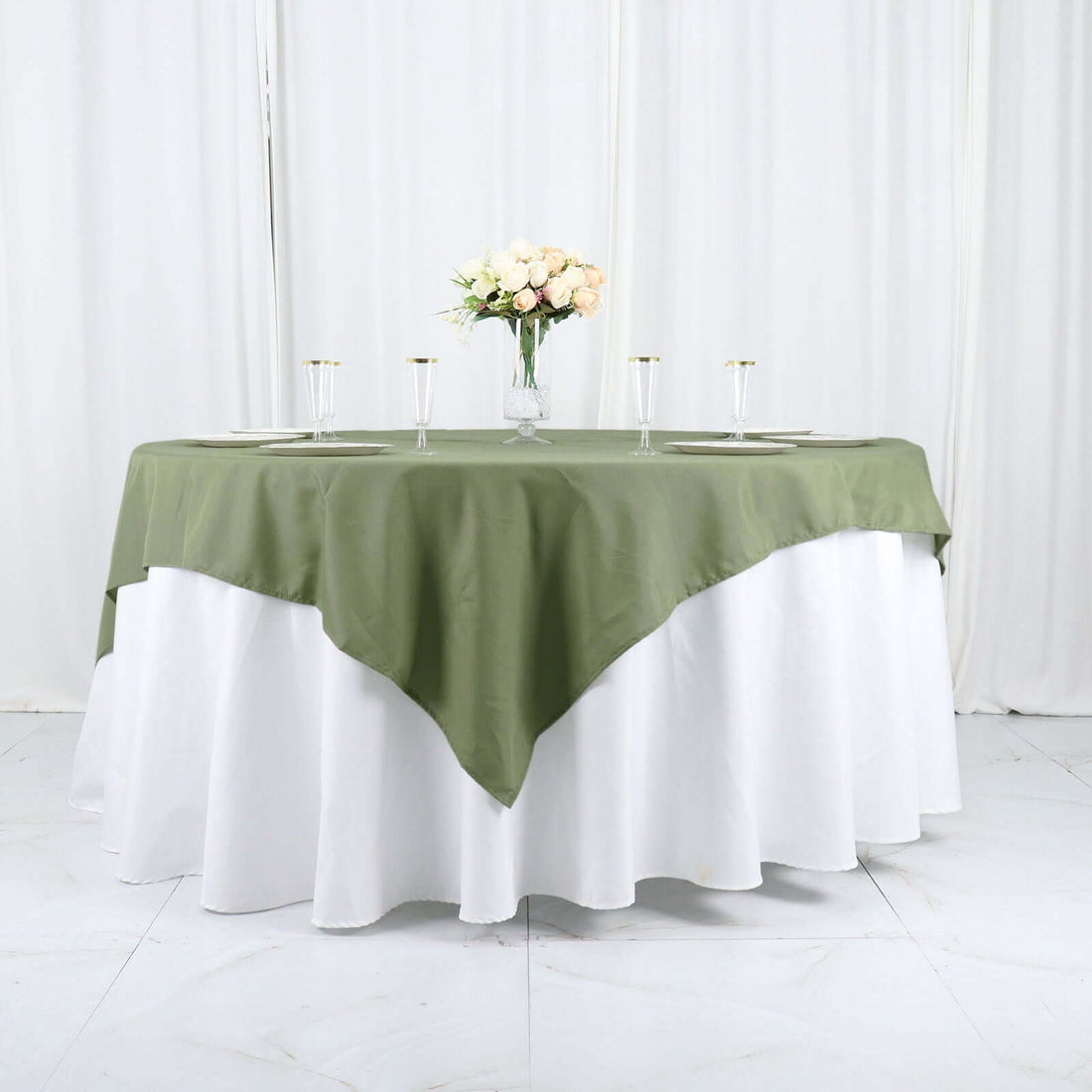 Green and white tablecloth set on a round table with floral centerpiece.