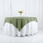 Green and white tablecloth set on a round table with floral centerpiece.