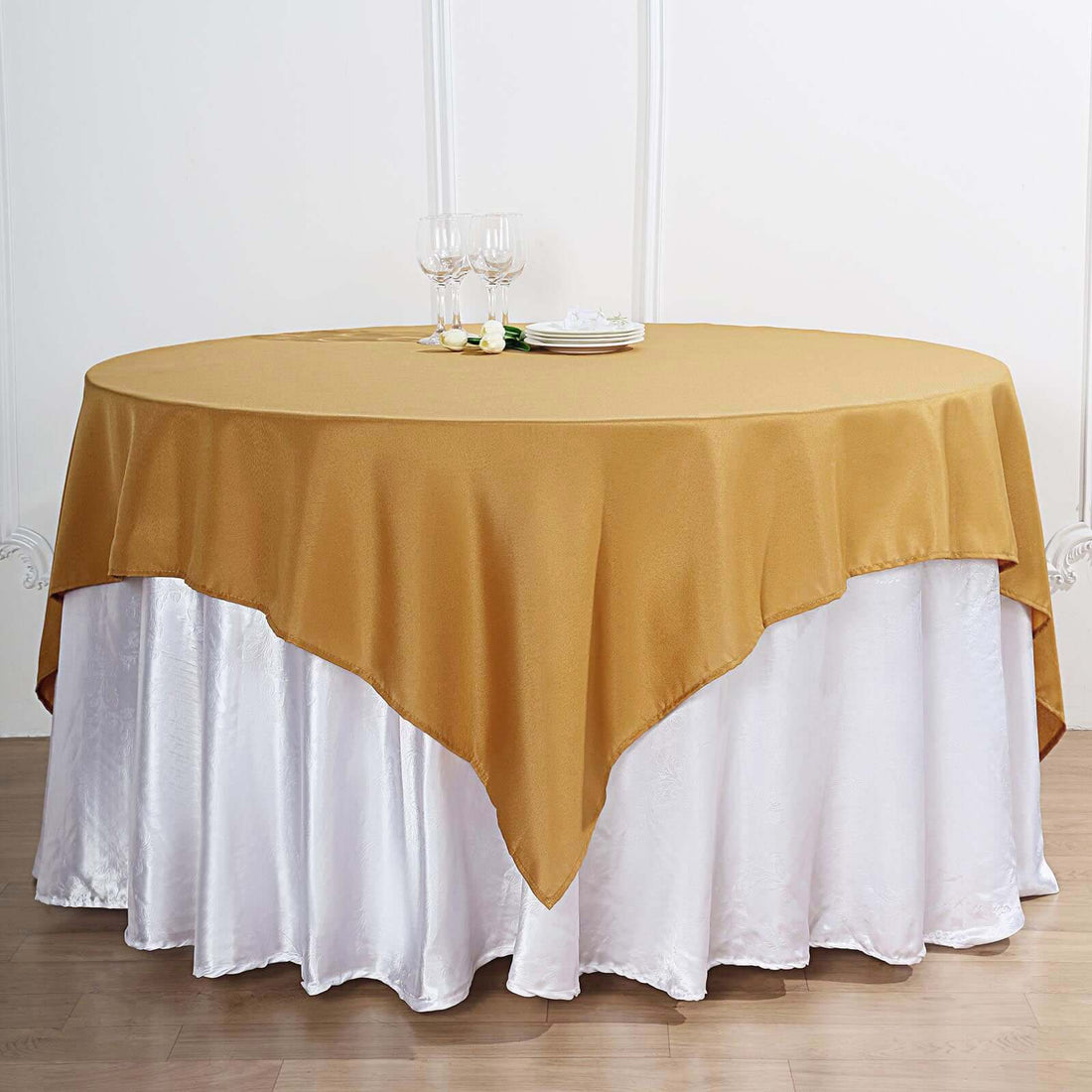 Round gold tablecloth draped over a white table skirt.