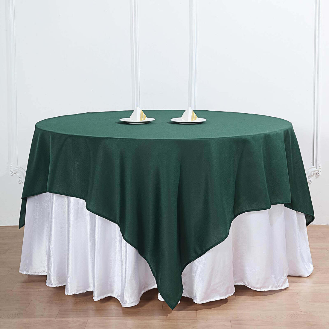 Green tablecloth draped over a white table with decorative plates.