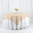 Beige round tablecloth draped elegantly over a white table with floral centerpiece.