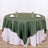 Round dark green tablecloth draped over a white table with wine glasses and napkins.