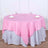 Round table set with pink and silver tablecloths, glasses, and napkins.