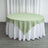 Round table with green and white tablecloth in a studio setting.
