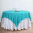 Turquoise tablecloth draped over a white table for elegant dining.