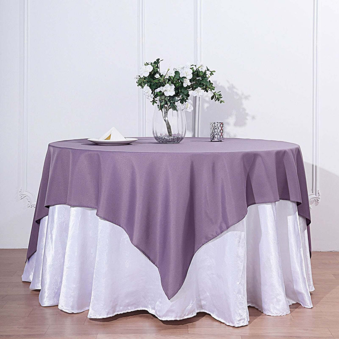 Purple tablecloth draped elegantly over a white skirted table with floral centerpiece.