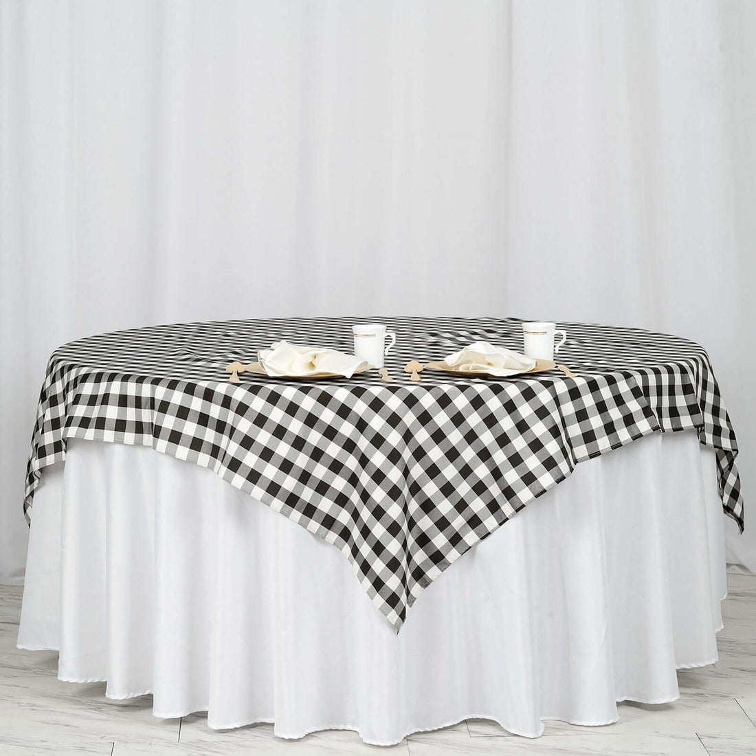 Black and white checkered tablecloth on a round table with white skirt