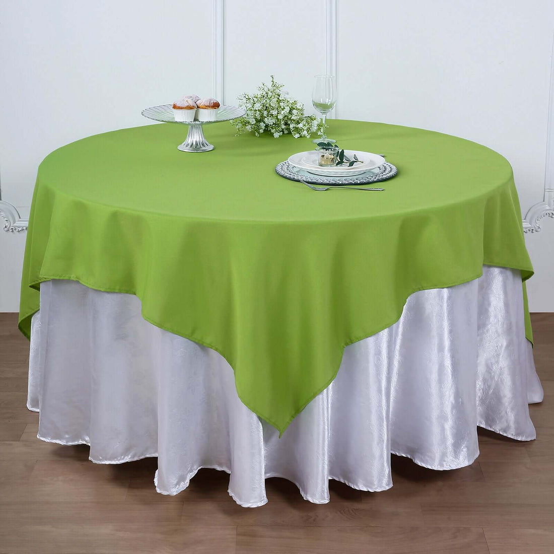 Green round tablecloth draped over a white satin table skirt.