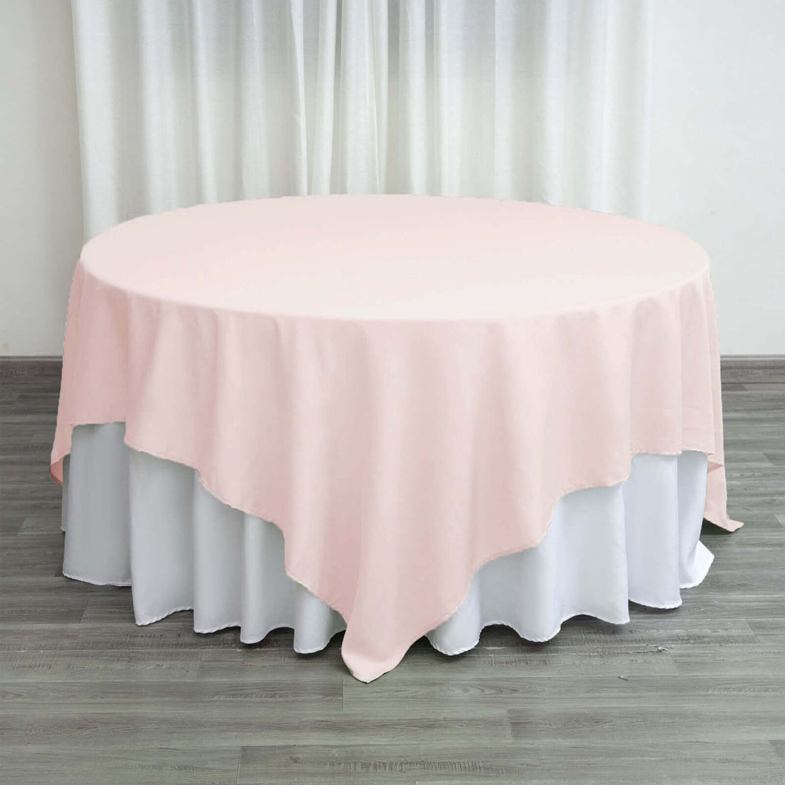 Round pink tablecloth on a white table in a staged setting.