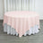 Round pink tablecloth on a white table in a staged setting.