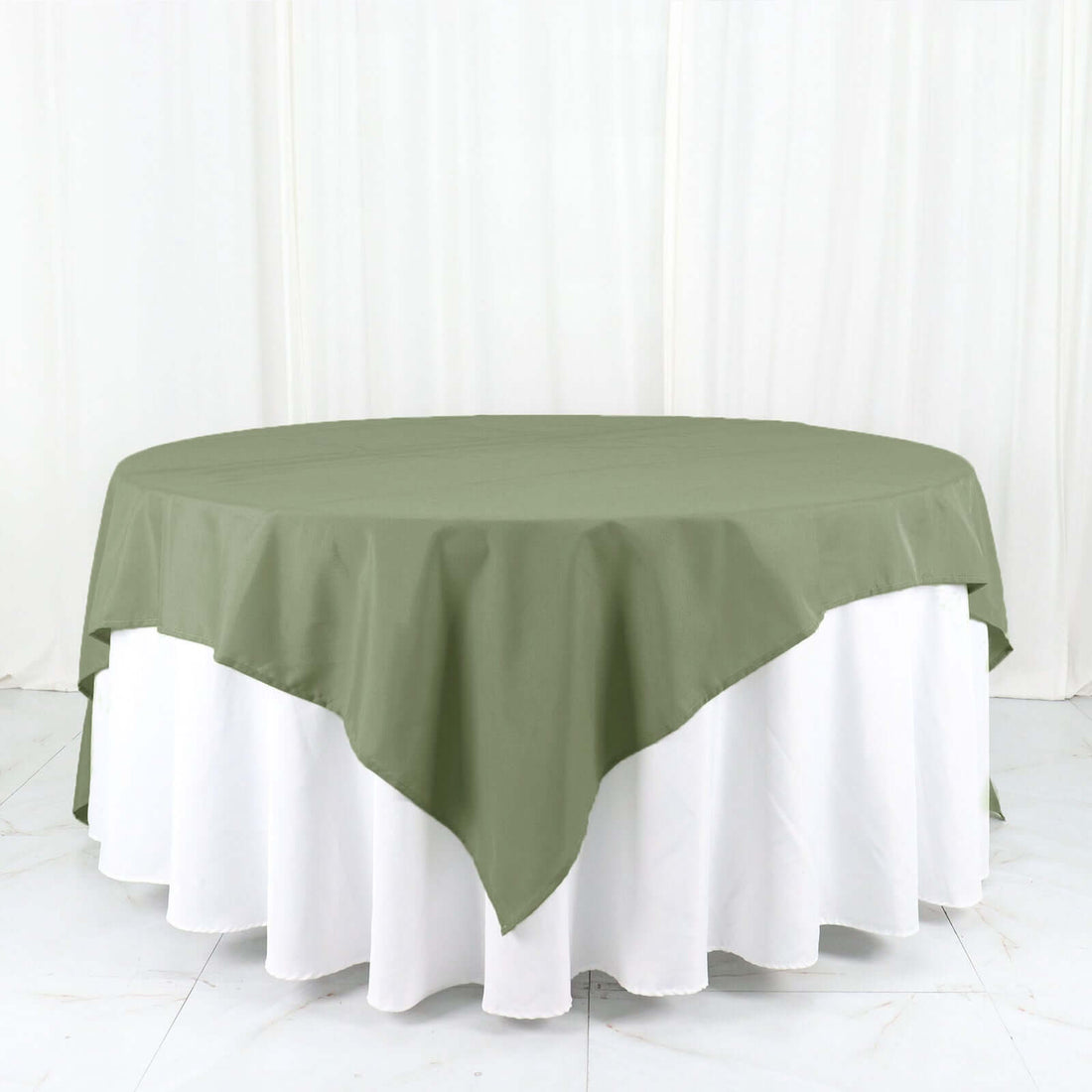 Round green tablecloth draped over a white table.