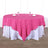 Pink tablecloth draped over a round table set with glasses and napkins.