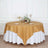 Round gold satin tablecloth on a dining table with elegant decor.
