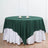 Green tablecloth draped over a round table with white skirt.