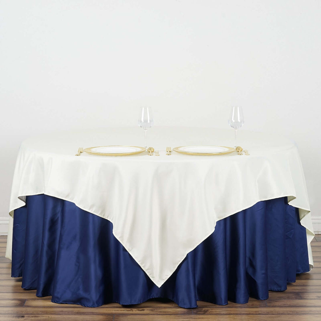 Elegant table setting with cream and navy tablecloth, plates, and wine glasses.