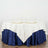 Elegant table setting with cream and navy tablecloth, plates, and wine glasses.