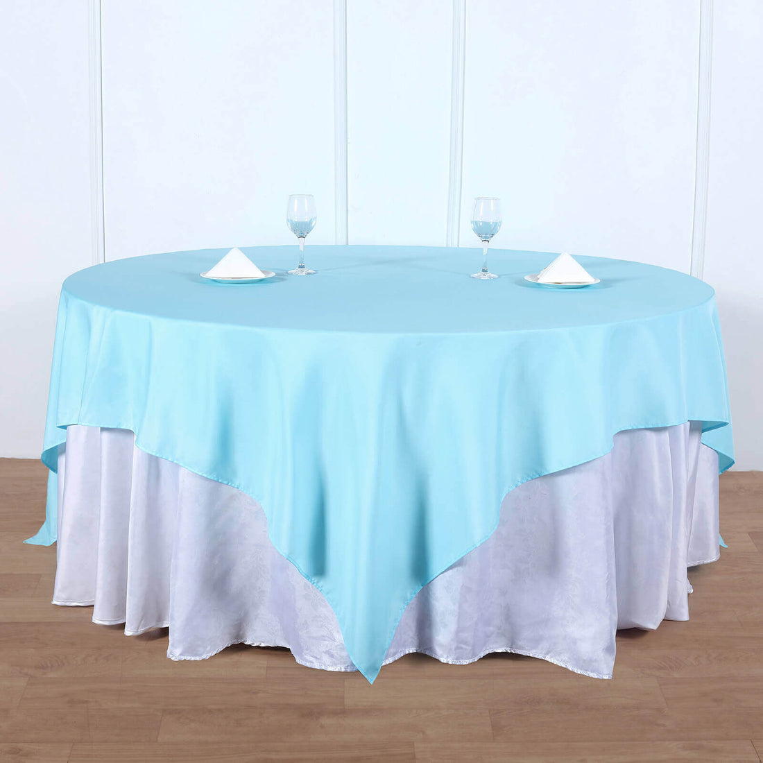 Round table set with a light blue tablecloth and white linens.