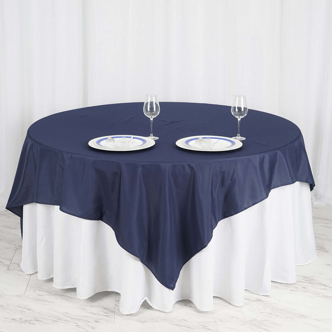 Navy tablecloth draped over round table with plates and glasses