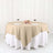 Beige round tablecloth draped over a round table with plates and wine glasses.