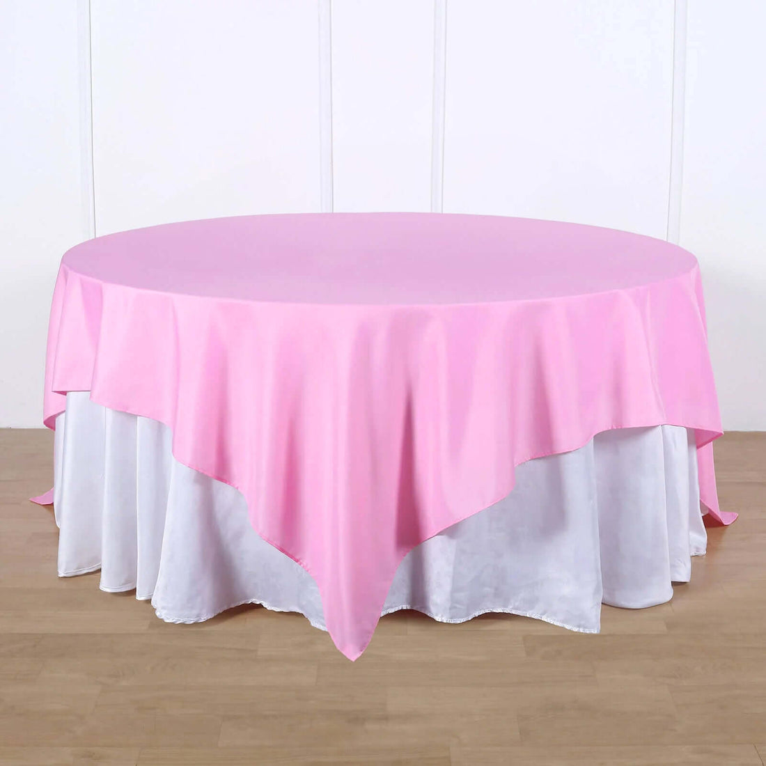 Round pink tablecloth draped over a white table.