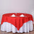 Red tablecloth draped over a round table set with glasses and napkins.