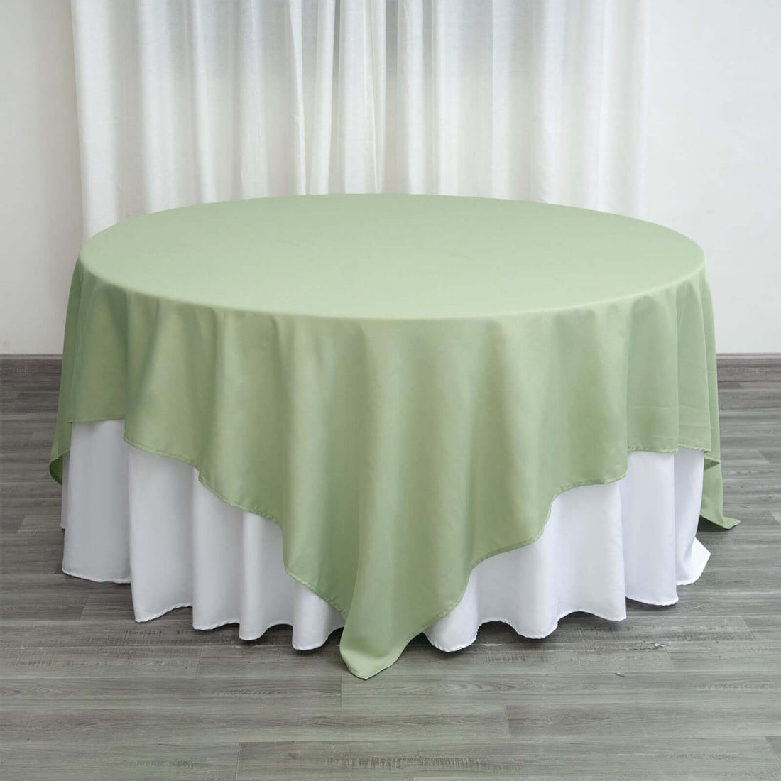 Round green tablecloth draped over a white table.