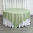Round green tablecloth draped over a white table.
