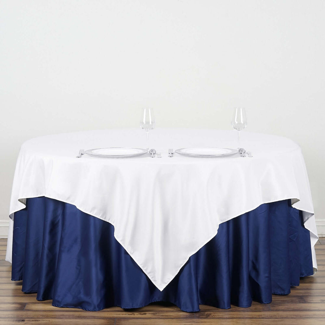 Round table dressed with white and navy tablecloth, set for dining.