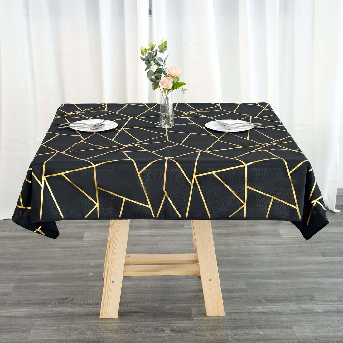 Black tablecloth with gold geometric design on a wooden table.