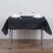 Black tablecloth on a dining table set with glasses and napkins.