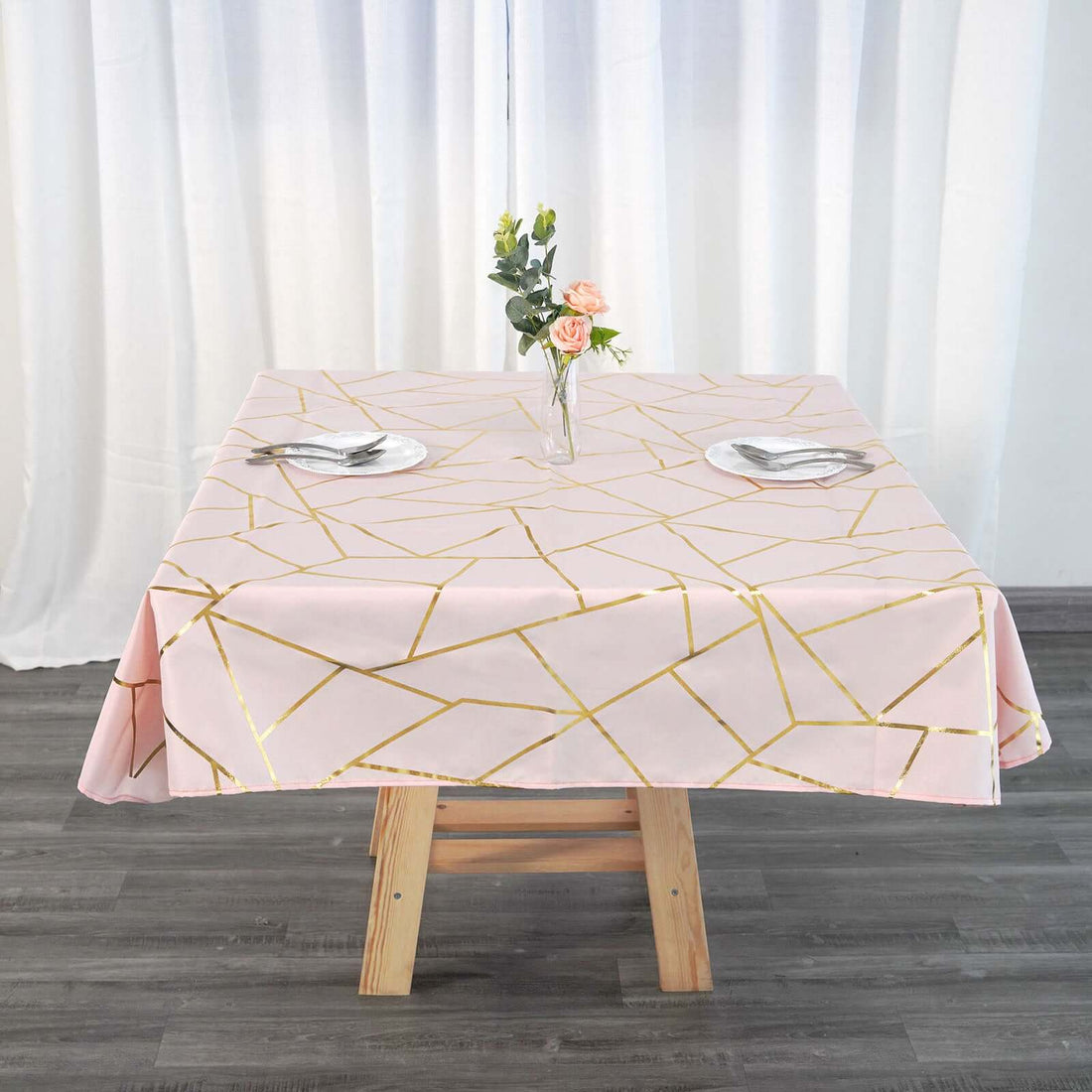 Pink geometric tablecloth with gold accents on a wooden table.