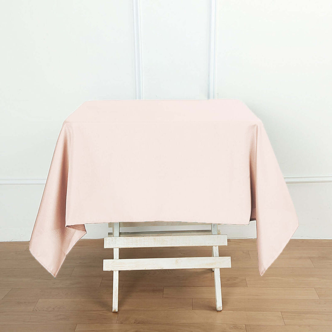 Pink tablecloth draped over a white wooden table in a simple setting.